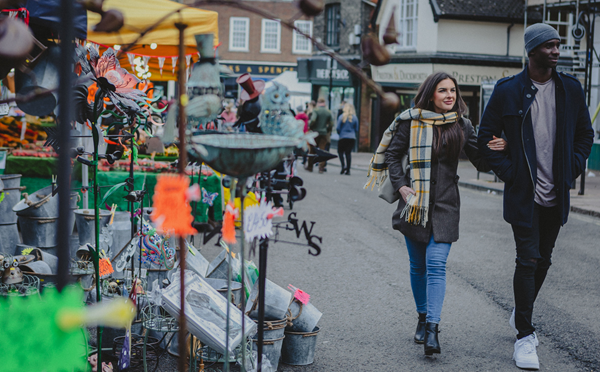 A woman and man walking though Bury St Edmunds Market